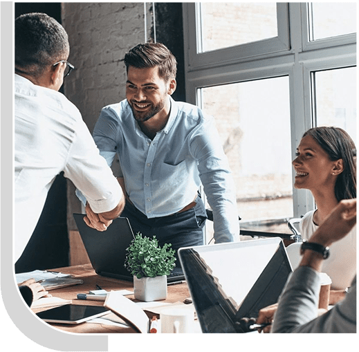 A group of people sitting around a table shaking hands.